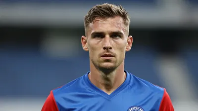 Mid-30s Sarpsborg 08 midfielder, athletic build, intense gaze, head-and-shoulders shot, wearing a plain blue jersey with...